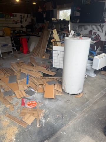 Garage cleanout with old water heater tank, flooring planks, tools and toilet fixture in Chicopee MA
