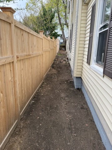 Side yard walkway along wooden privacy fence swept and raked clean after debris and brush removal