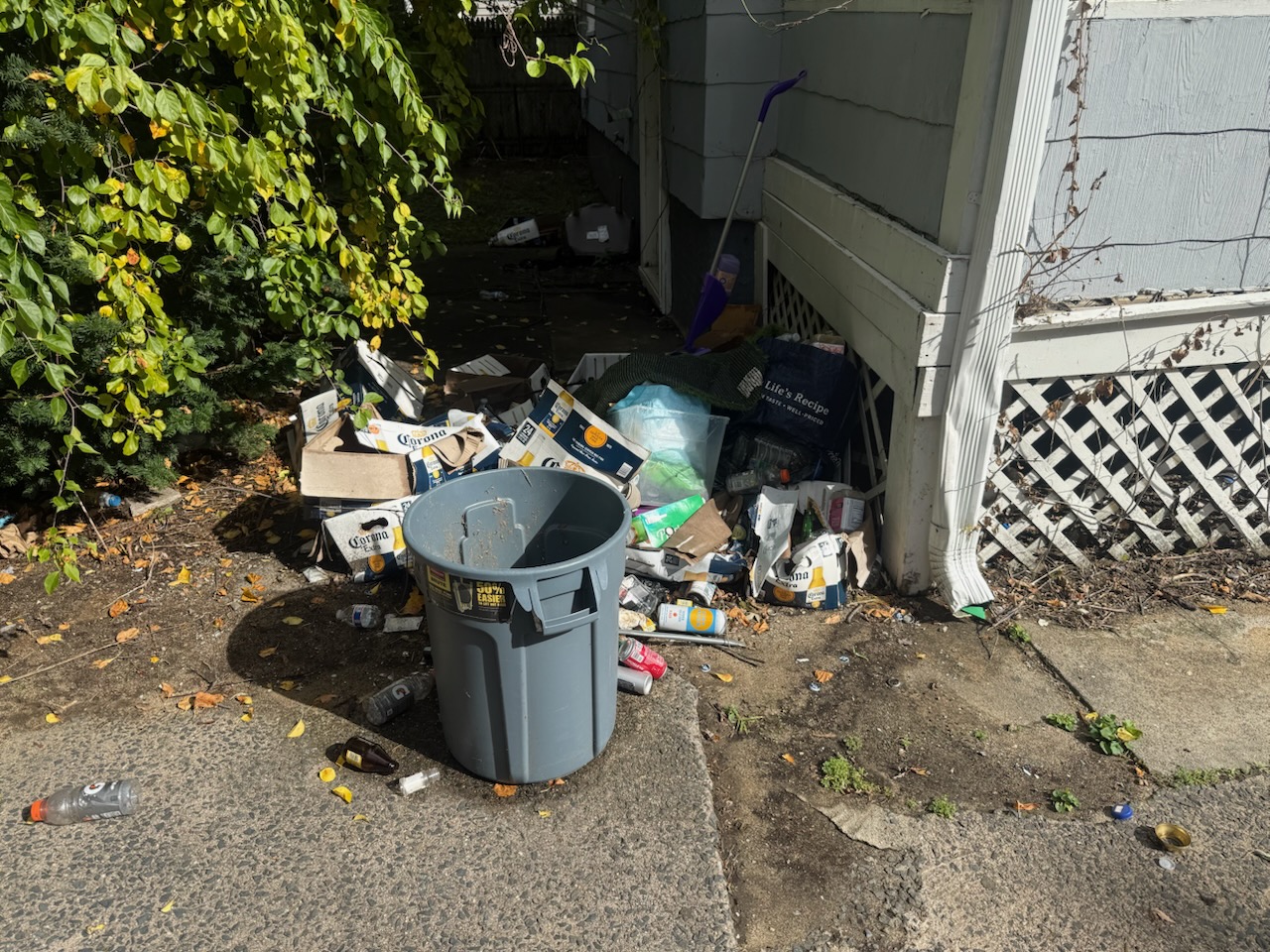 Residential alley and side porch trash, empty cans, boxes and household debris in Holyoke MA