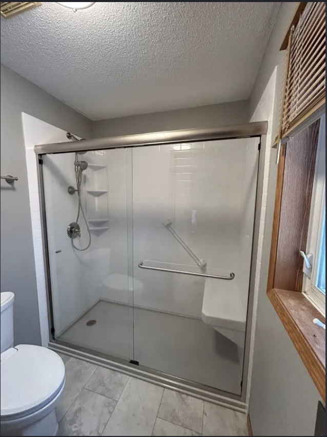 Walk-in shower conversion with brushed nickel trim, grab bar, and bench