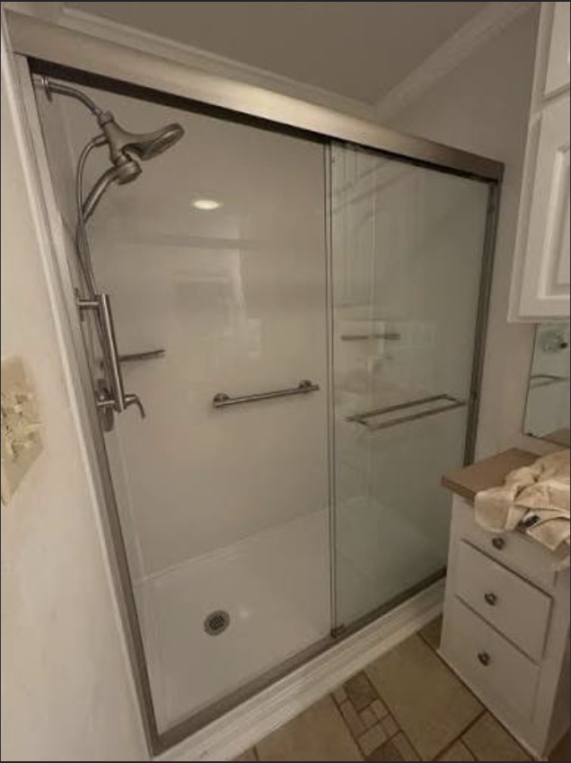 Low-barrier walk-in shower with bypass glass sliding doors and towel bar