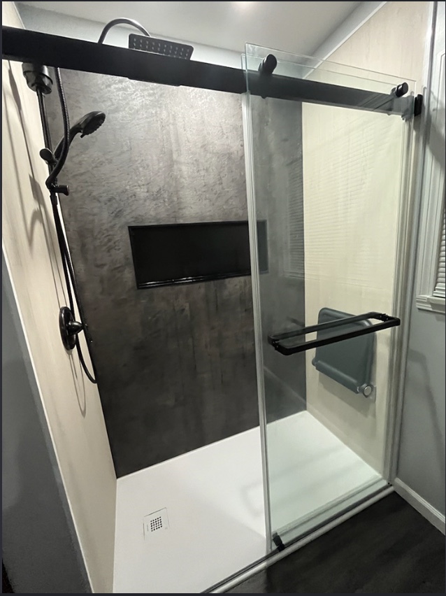 Modern walk-in shower with sliding glass door and matte black fixtures