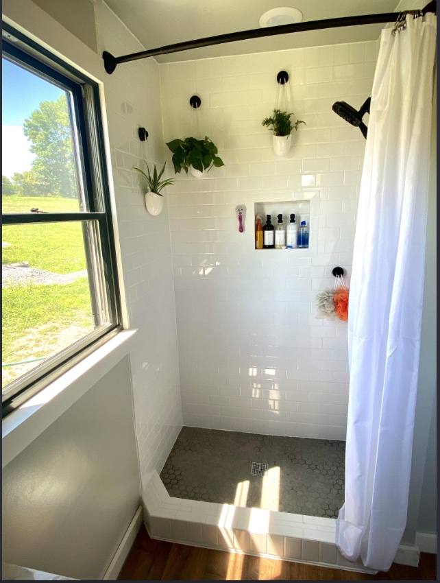 White subway tiled walk-in shower with hex tile floor and niche