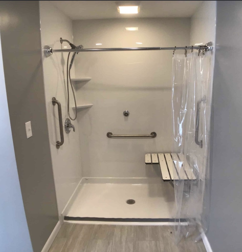 Barrier-free walk-in shower conversion with fold-down wooden bench and grab bars