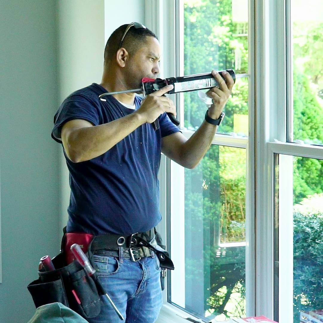 A licensed installer sealing and insulating a home window