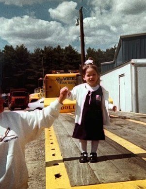 Jade as a little girl on the deck of a rollback at the family tow yard