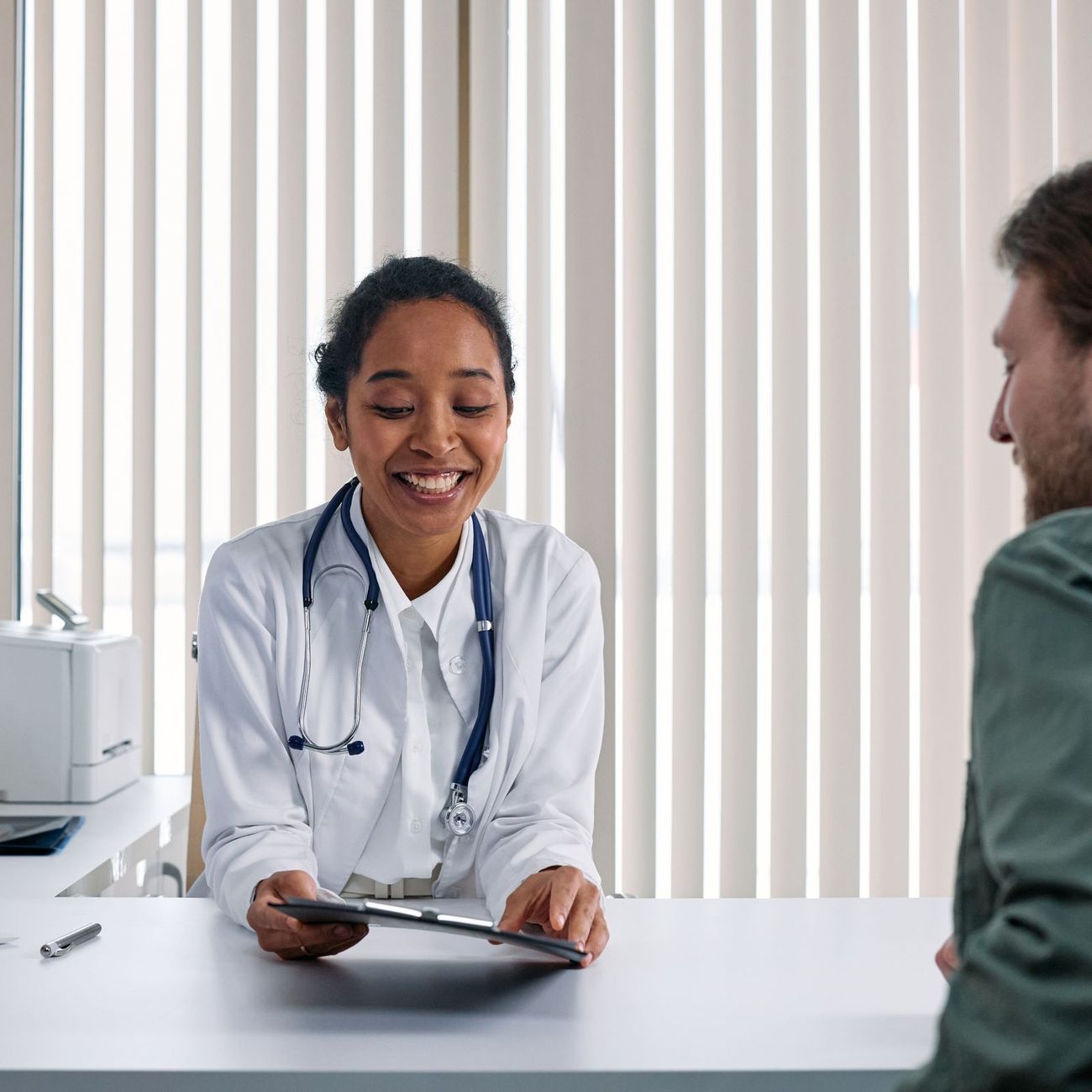 Ärztin im Gespräch mit einem Patienten am Praxistisch