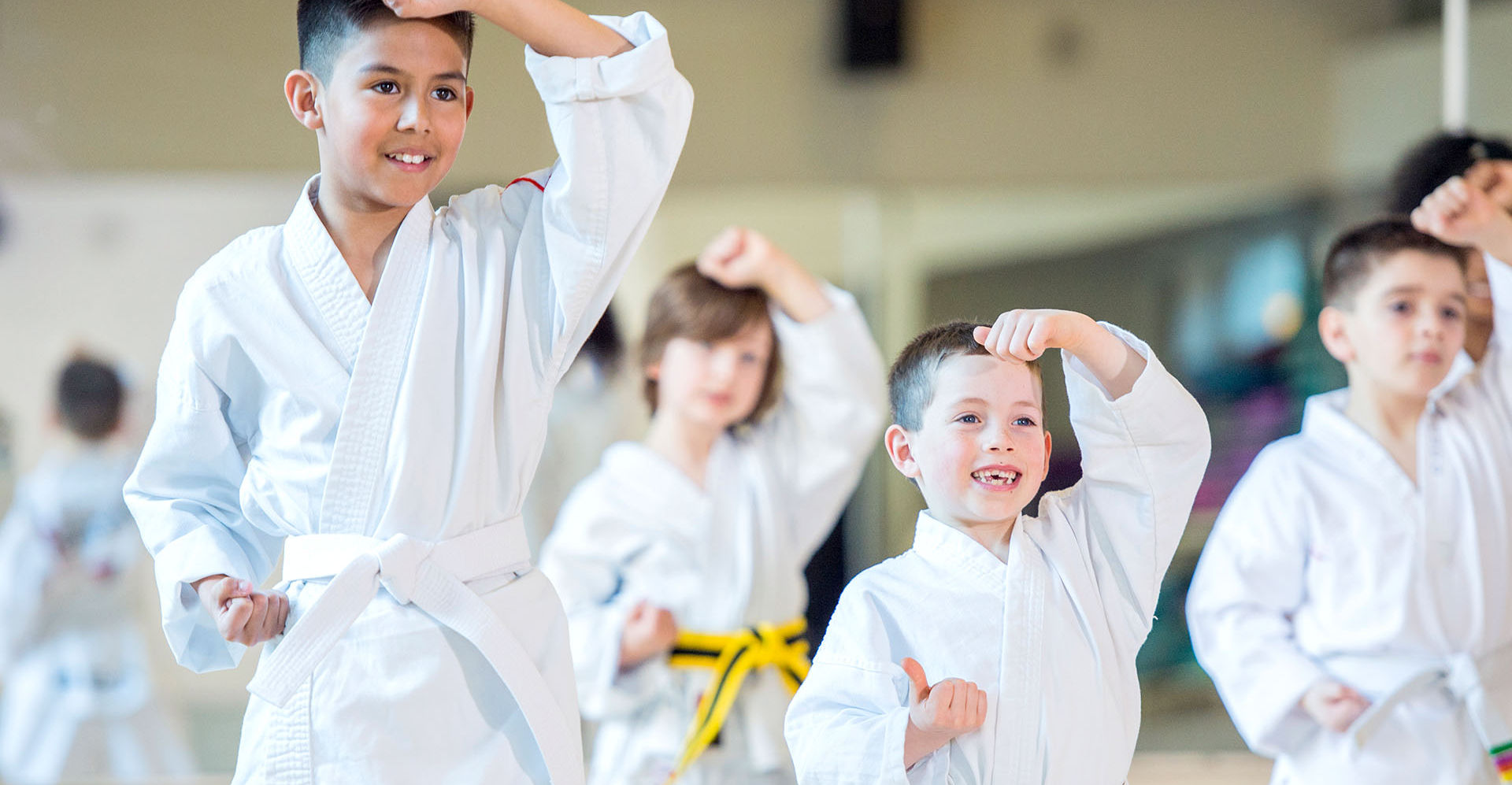 Children in clean white Tae Kwon Do uniforms practicing inside the dojang
