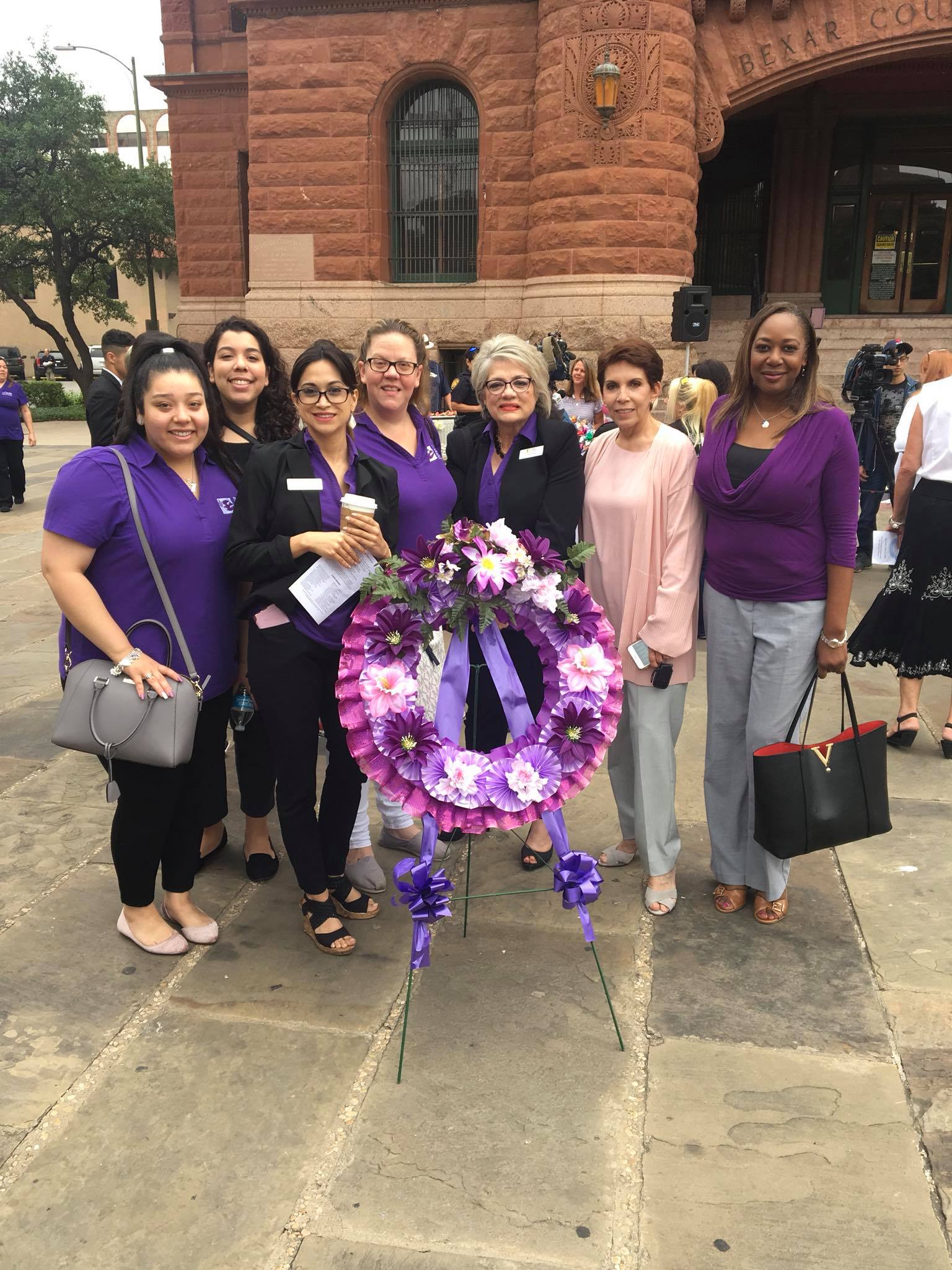 Gwendolen Wilder with domestic violence advocates and community leaders standing with a purple memorial wreath