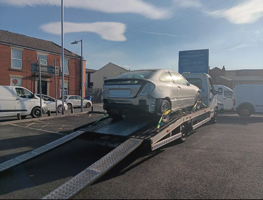 Mercedes coupe loaded and strapped down onto recovery truck ramps