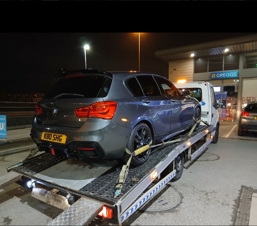 Abu Sultan Recovery flatbed truck transporting a grey BMW 1-Series M-Sport at night