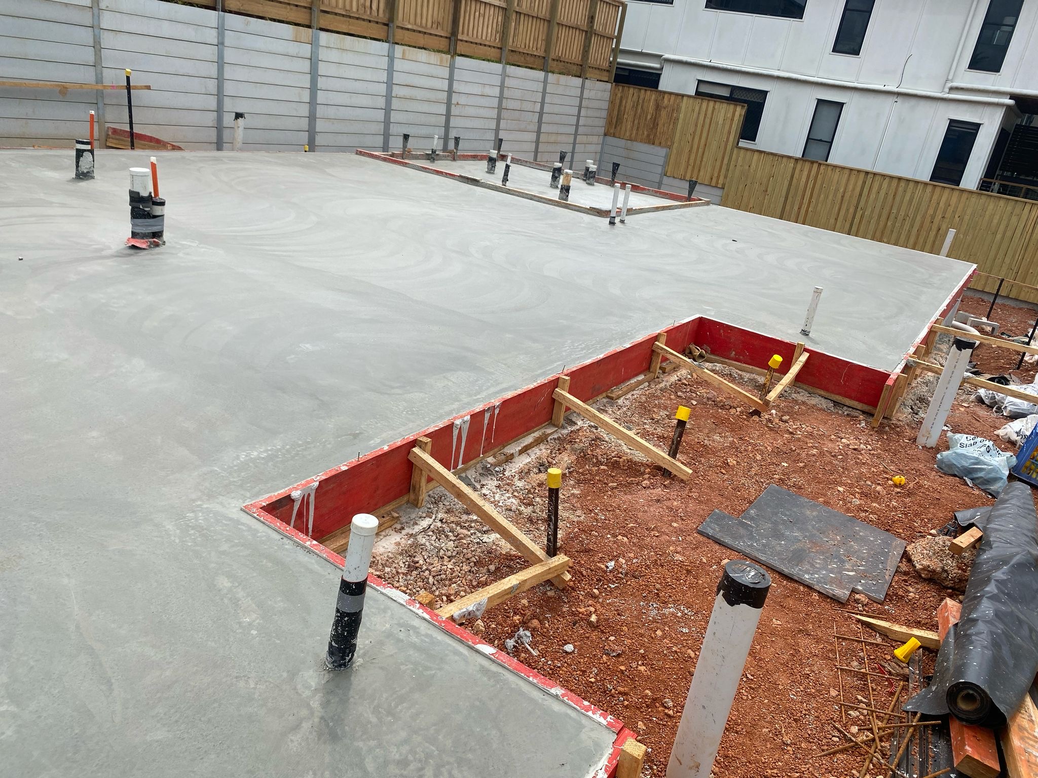 29 Musgrave St Wellington Point - Engineered structural ground slab pour with stepped boundary formwork, sub-slab plumbing penetration clusters, and acoustic concrete sleeper retaining wall