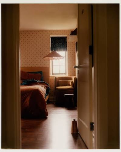 Cozy sunlit guest bedroom with armchair and lamp at Argyll House