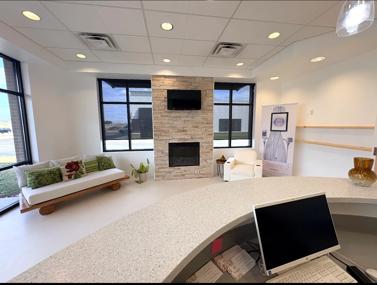 The Skin & Body Shop lobby in O'Fallon featuring modern fireplace, large windows, and comfortable guest seating