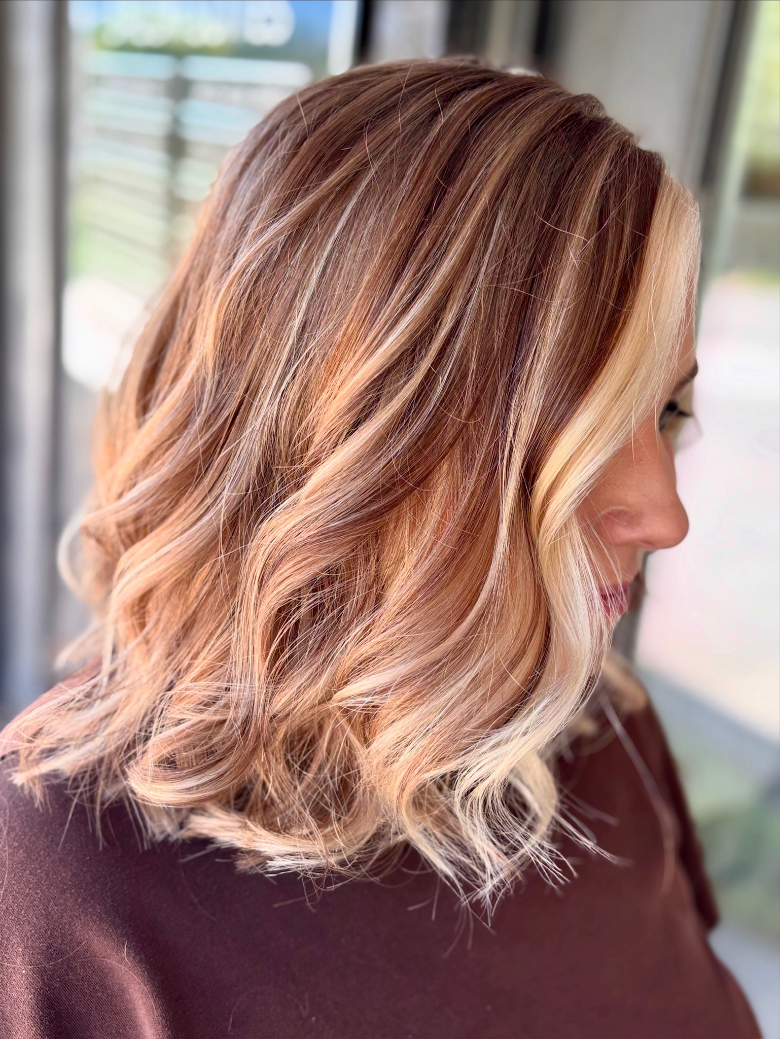 Warm dimensional strawberry blonde and copper highlighted lob with soft waves by Kalene