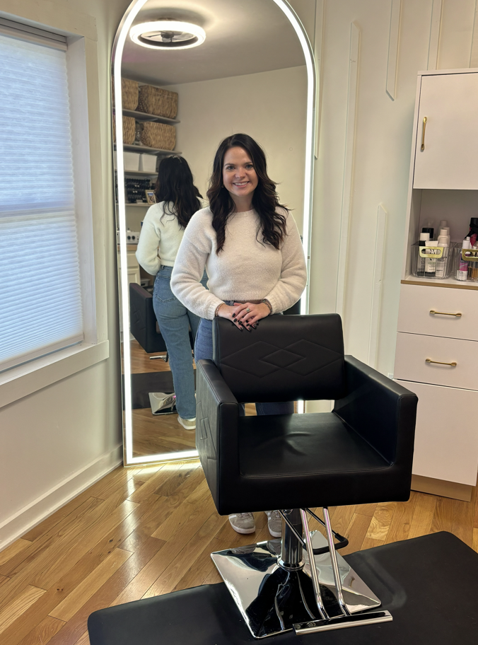 Kalene standing by the styling chair and illuminated arch mirror in her salon space