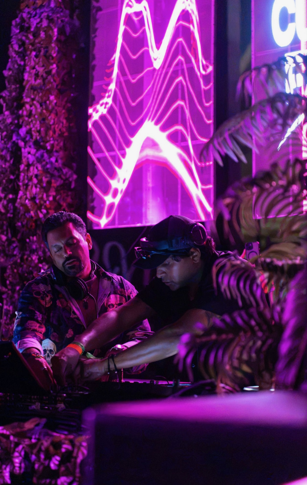 Curry Fury (GHANDI and Techno Dad) mixing behind the decks under vivid purple and magenta stage visuals