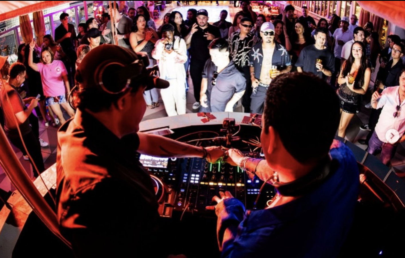 Curry Fury DJs mixing behind the decks overlooking a packed rooftop party crowd
