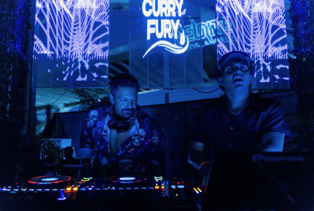 Curry Fury (GHANDI and Techno Dad) performing behind the decks beneath glowing blue Curry Fury stage visuals
