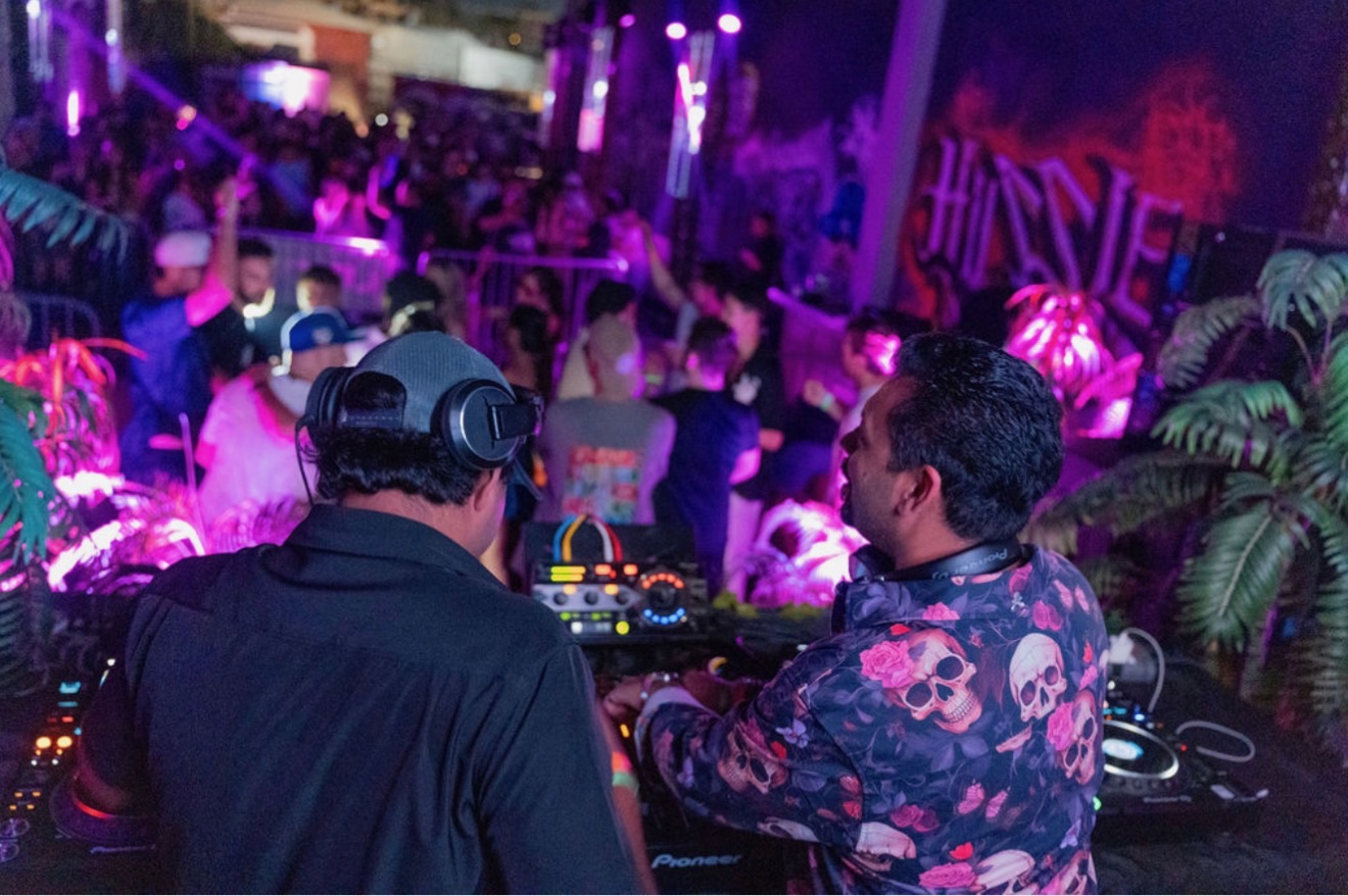 Curry Fury performing behind the Pioneer DJ decks facing an energized purple-lit crowd