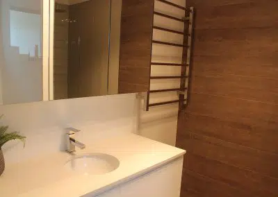 Contemporary timber wall bathroom vanity with white under-mount basin and heated towel rail