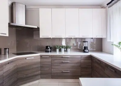 Modern kitchen renovation with white overhead cabinets and textured wood grain base drawers
