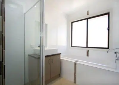 Bright bathroom renovation with bathtub, glass shower screen and vanity unit
