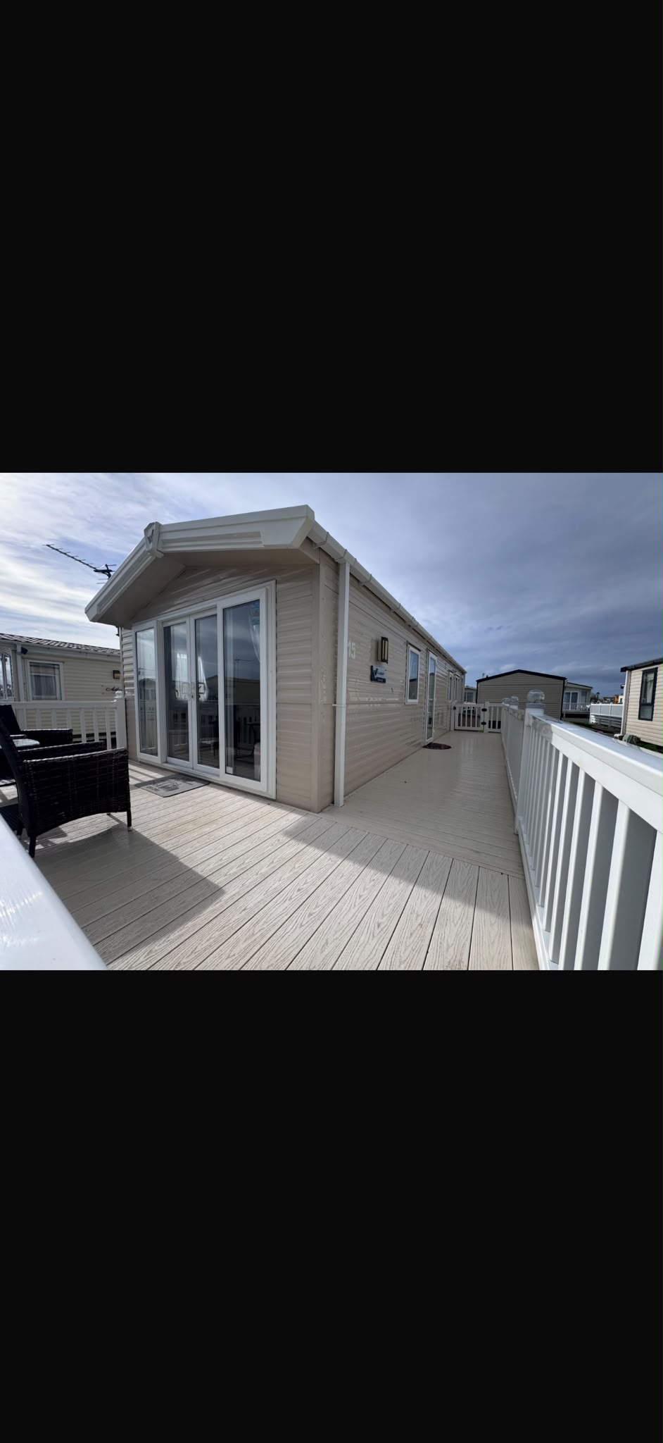 Outdoor decking area with comfortable outdoor chairs and table beside front patio doors