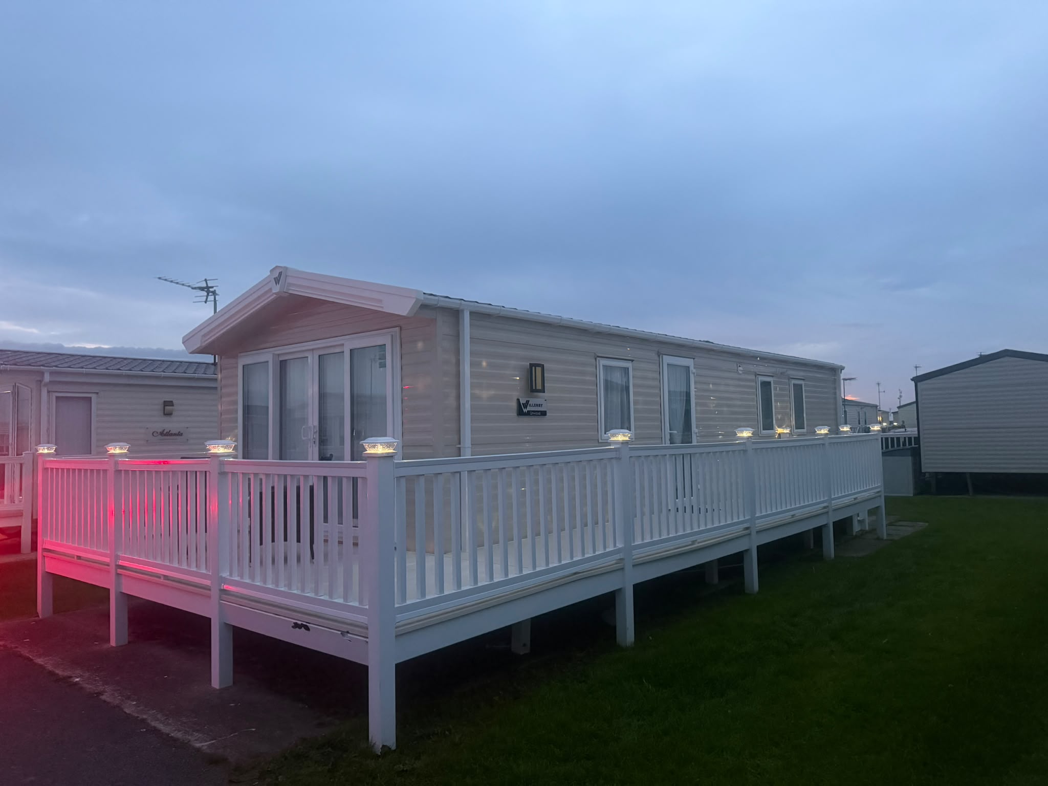The Family Hideaway caravan exterior at dusk with warm illuminated decking
