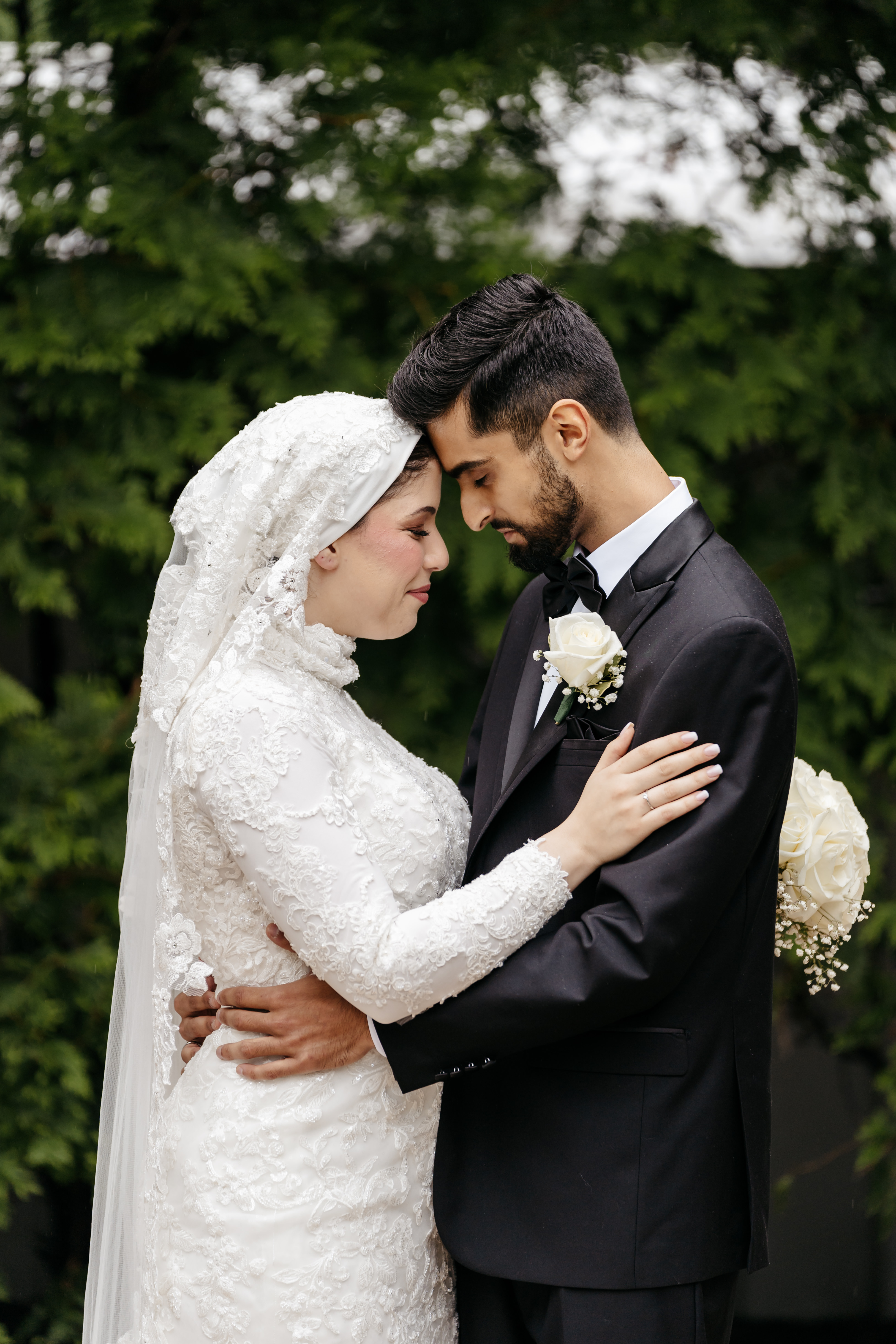 Bride and groom seated outdoors holding hands sharing a tender smile