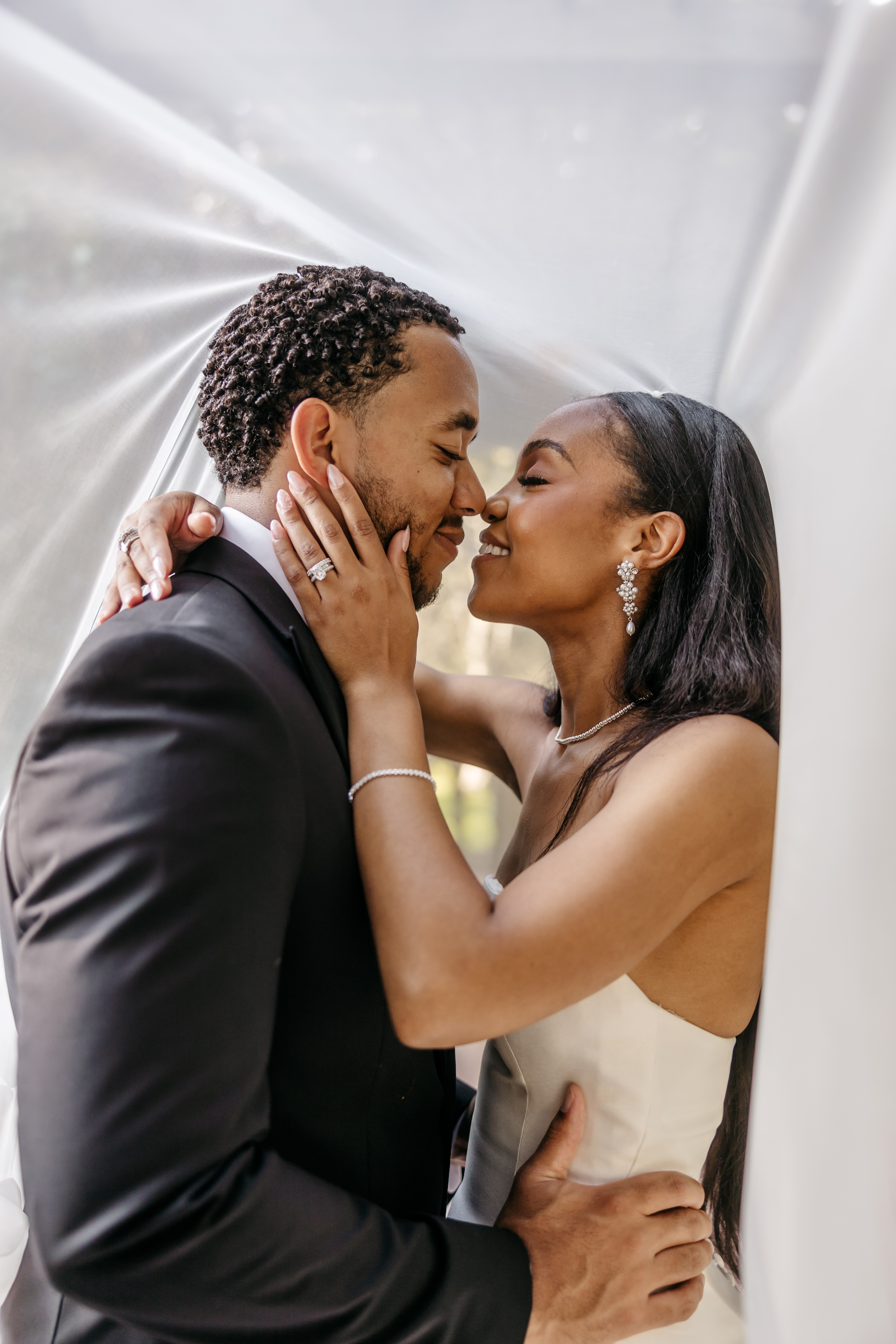 Intimate romantic portrait of bride and groom embracing under bridal veil