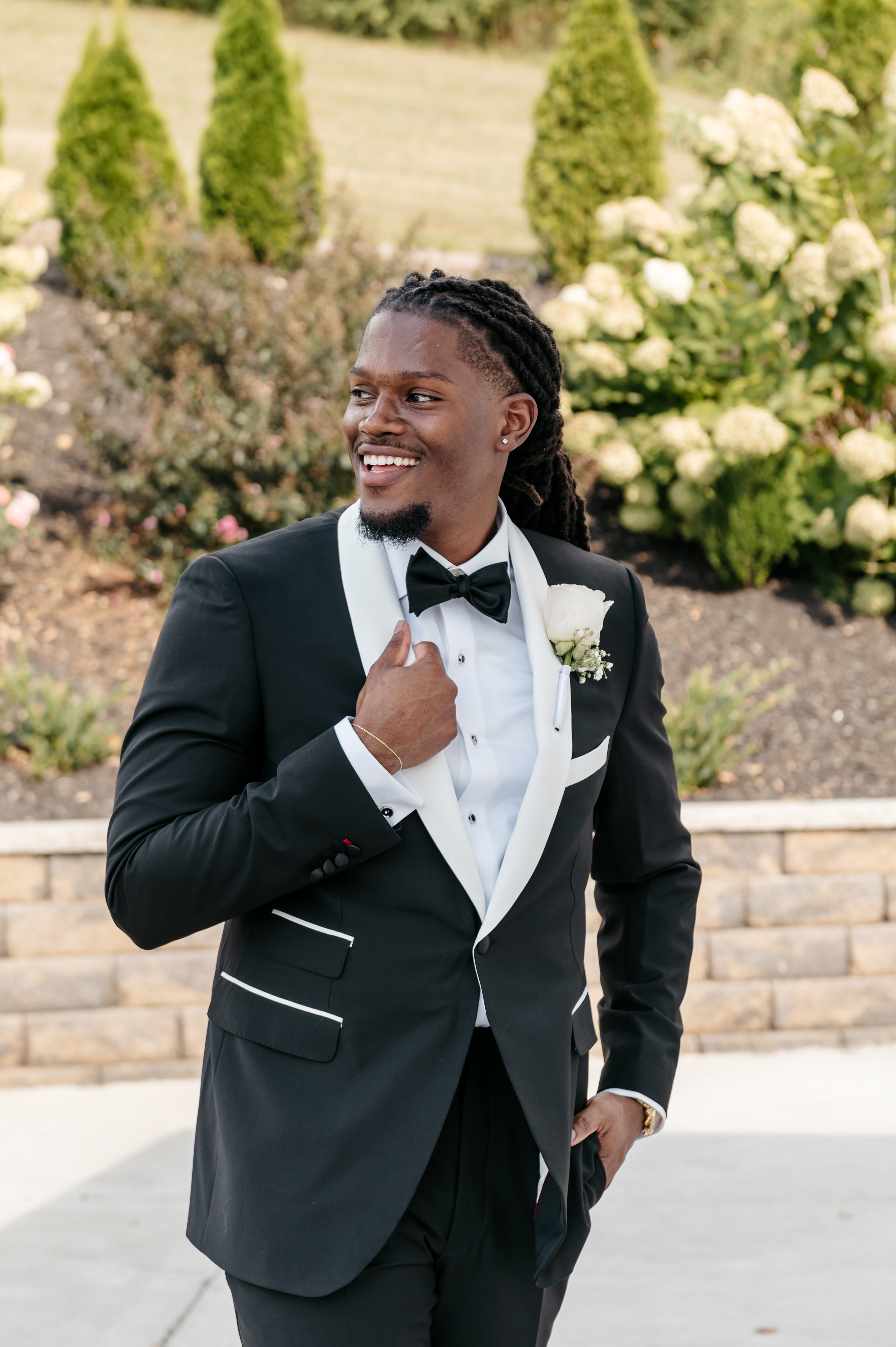Smiling groom in black tuxedo with white shawl lapel outdoors