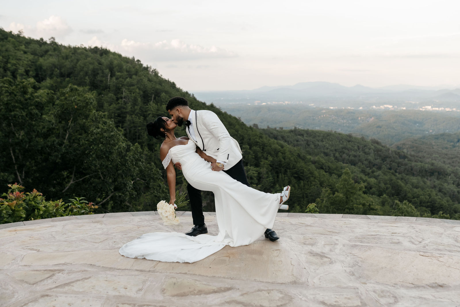 Romantic portrait of bride and groom dipping and kissing overlooking panoramic mountain views