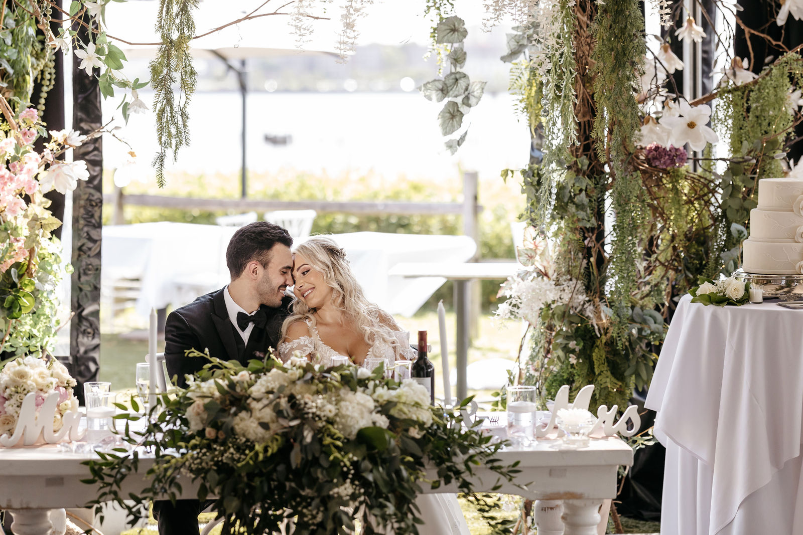 Bride and groom smiling together at floral sweetheart table