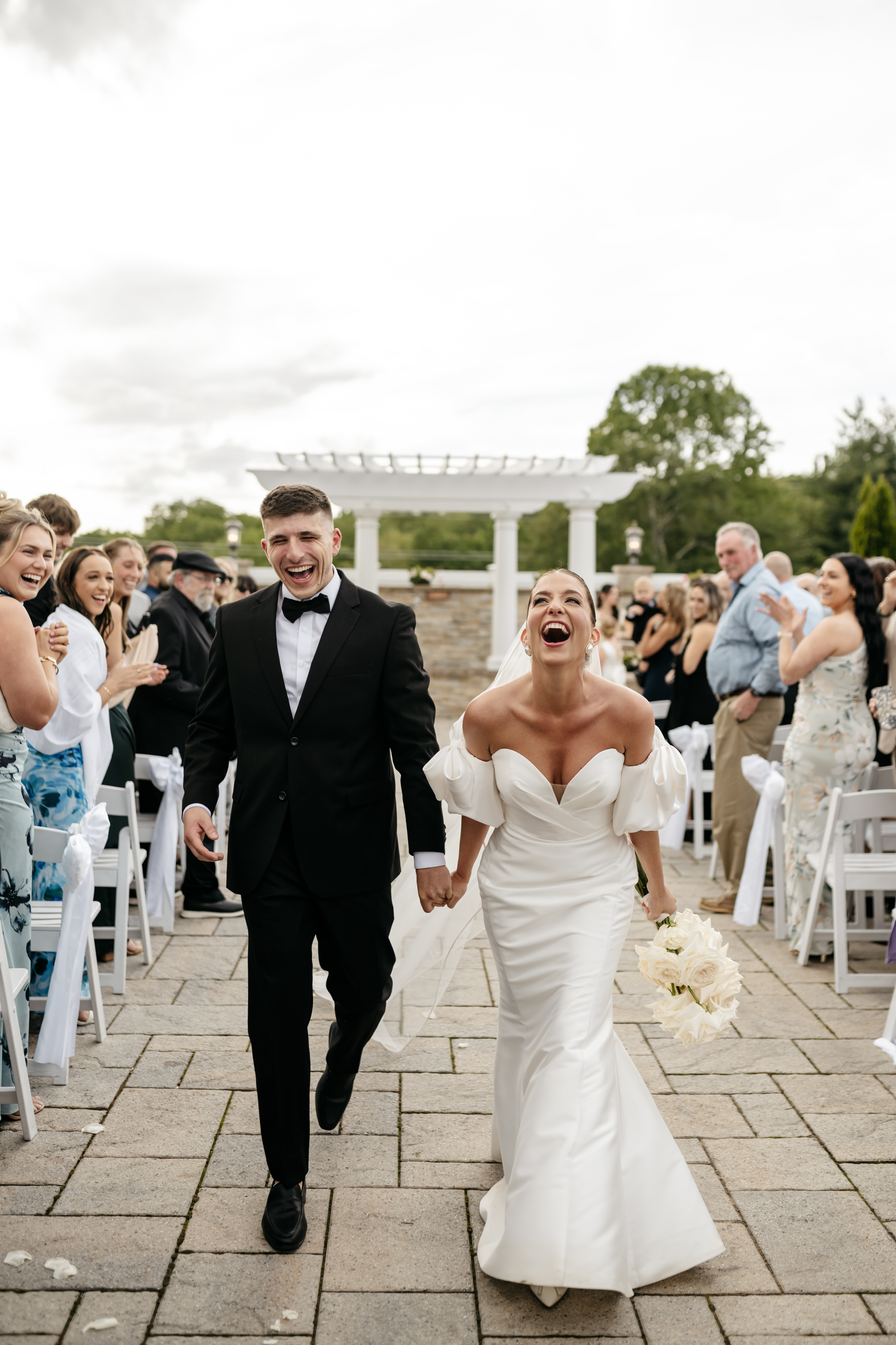 Joyful bride and groom celebrating down the outdoor ceremony aisle