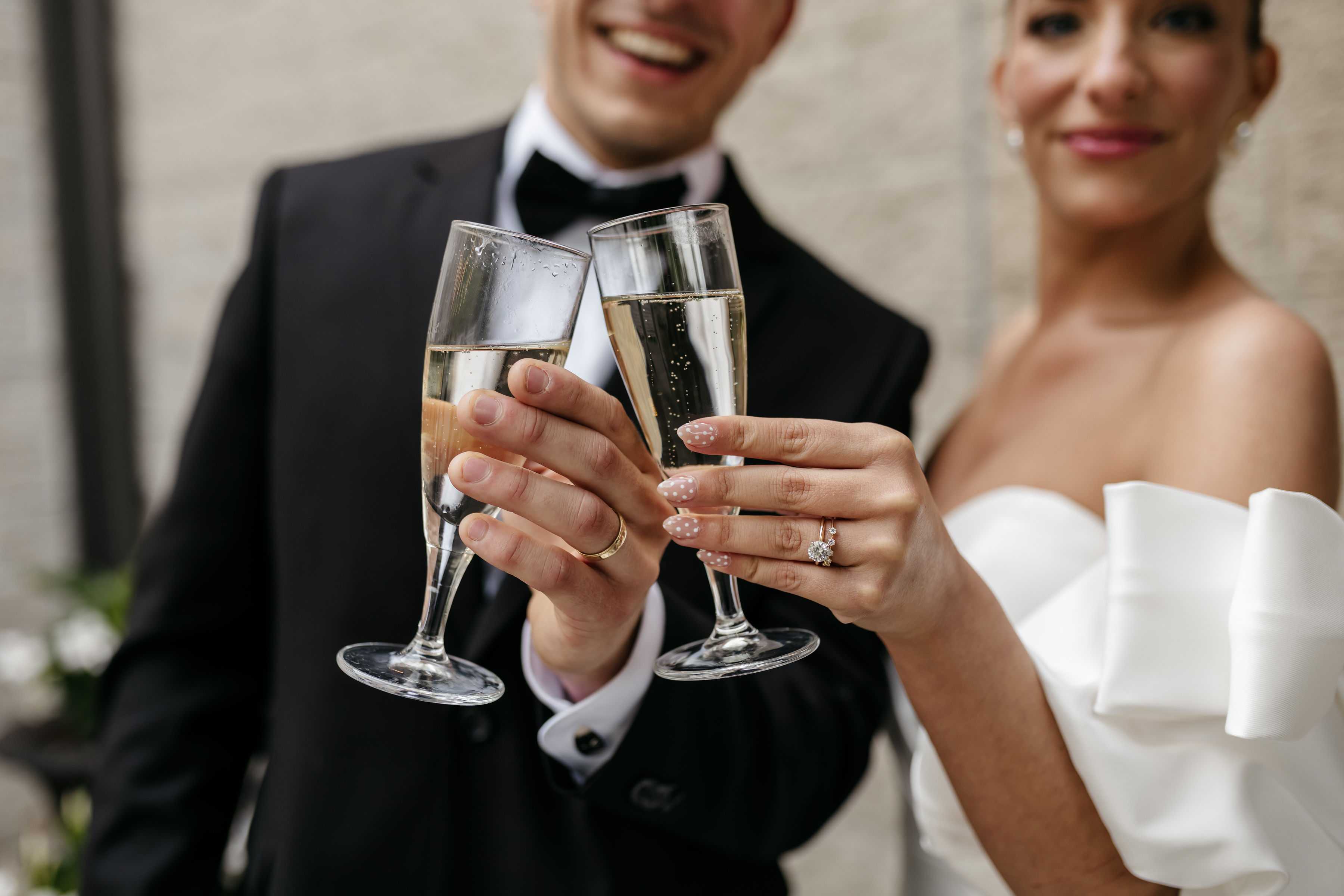 Close-up of bride and groom toasting with champagne flutes showing wedding rings