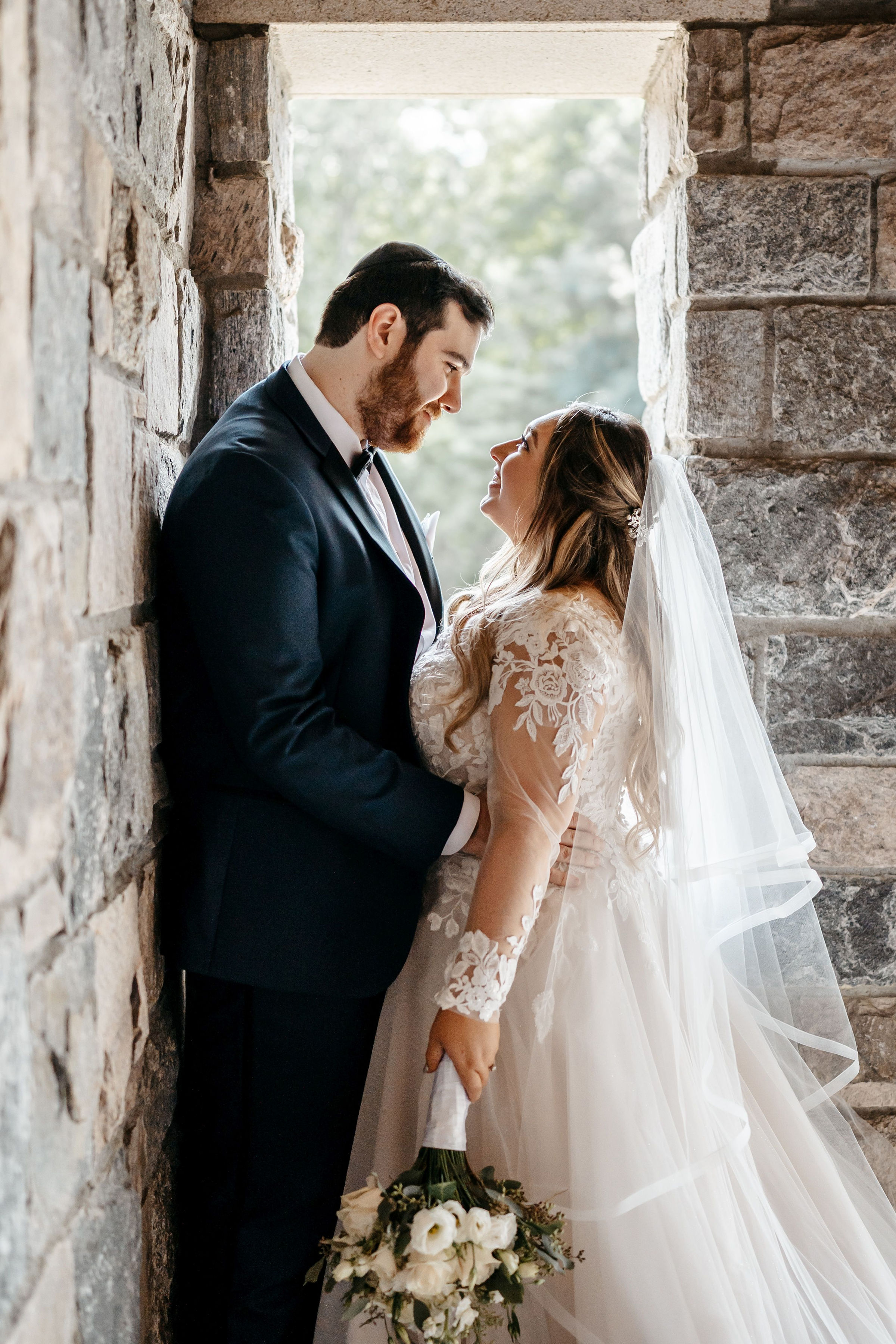 Bride and groom embracing in stone archway