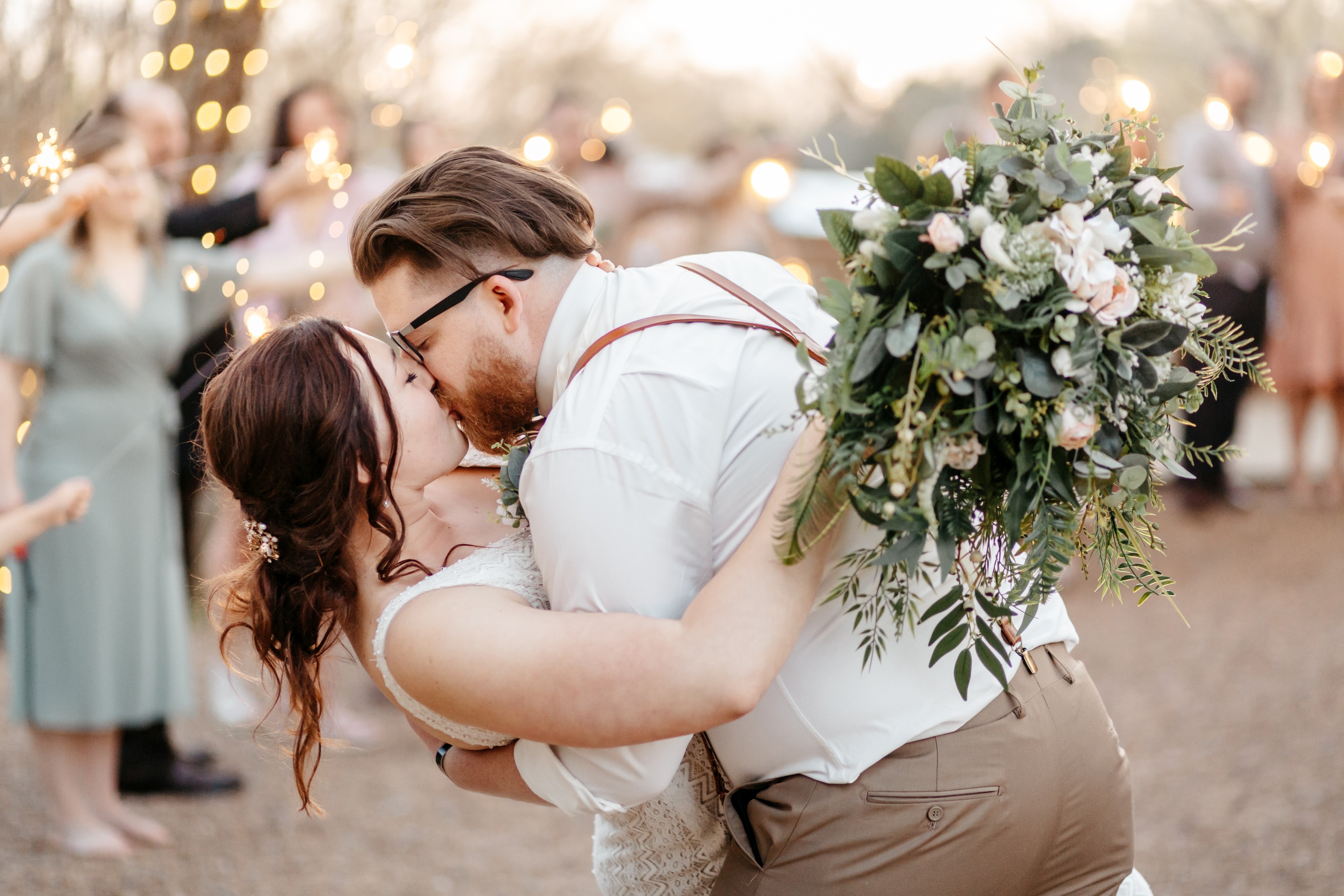 Romantic portrait of bride and groom kissing during sparkler send-off celebration