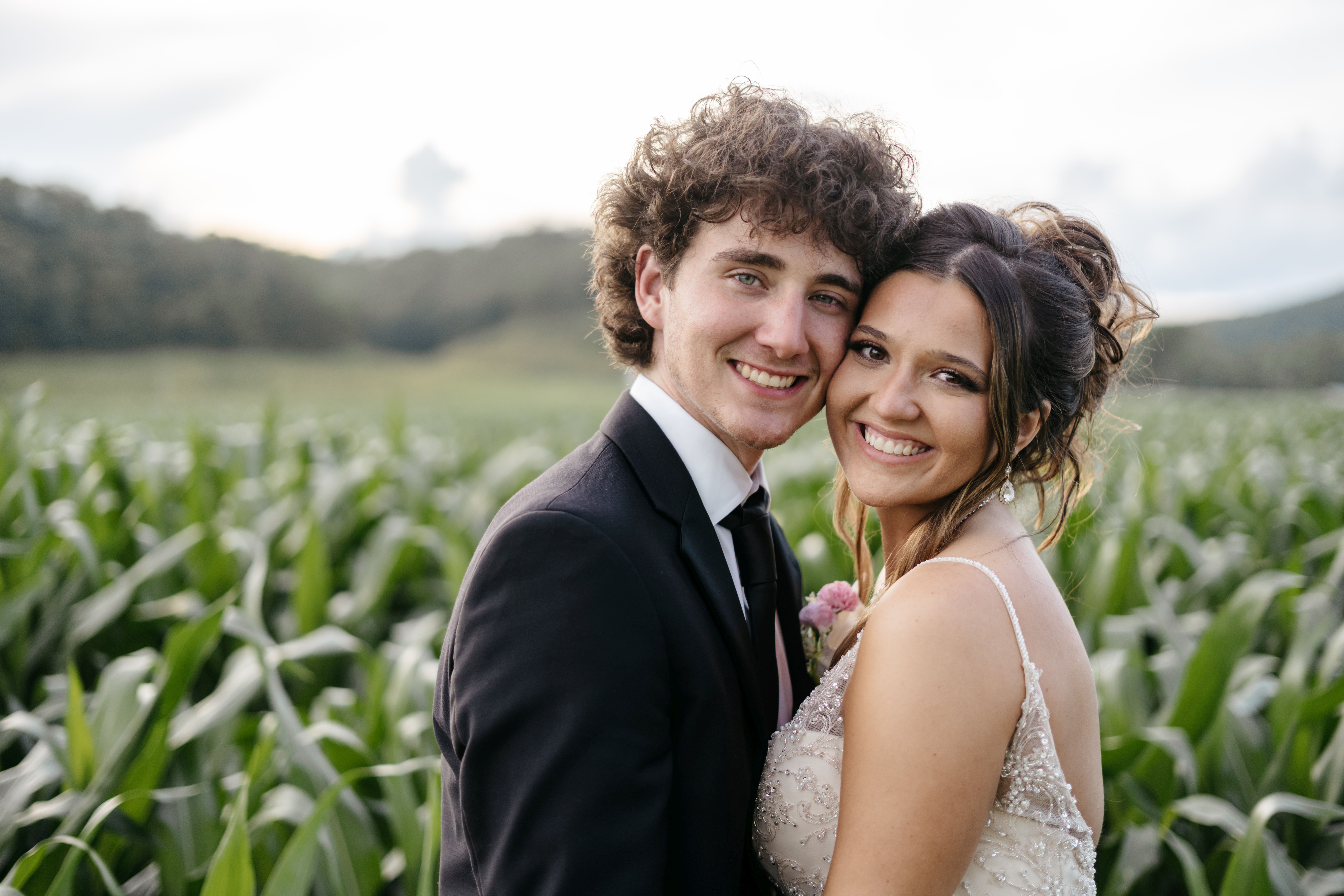 Romantic bride and groom smiling at each other with veil catching the sunlight beside white venue