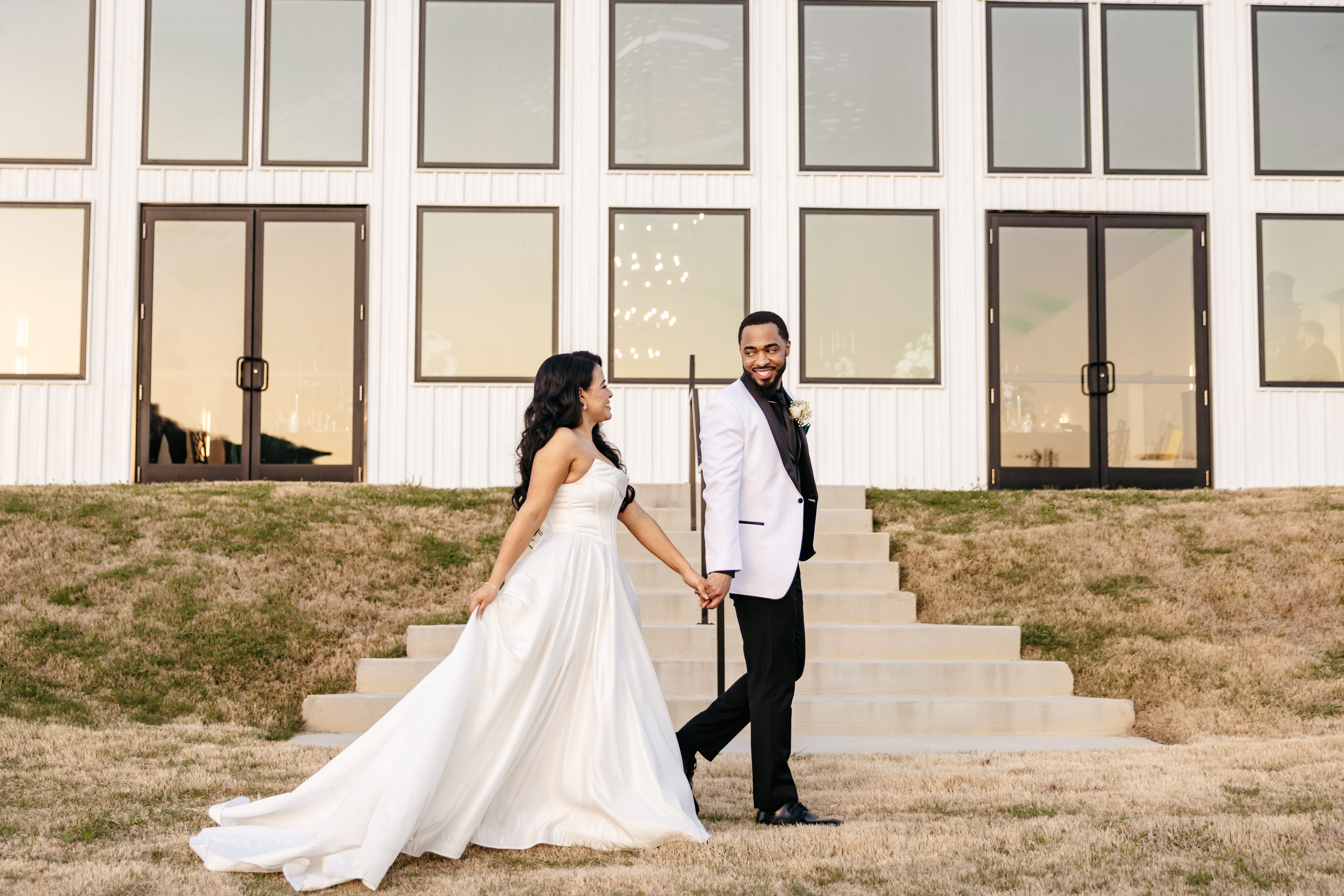 Bride and groom holding hands walking outside modern white venue