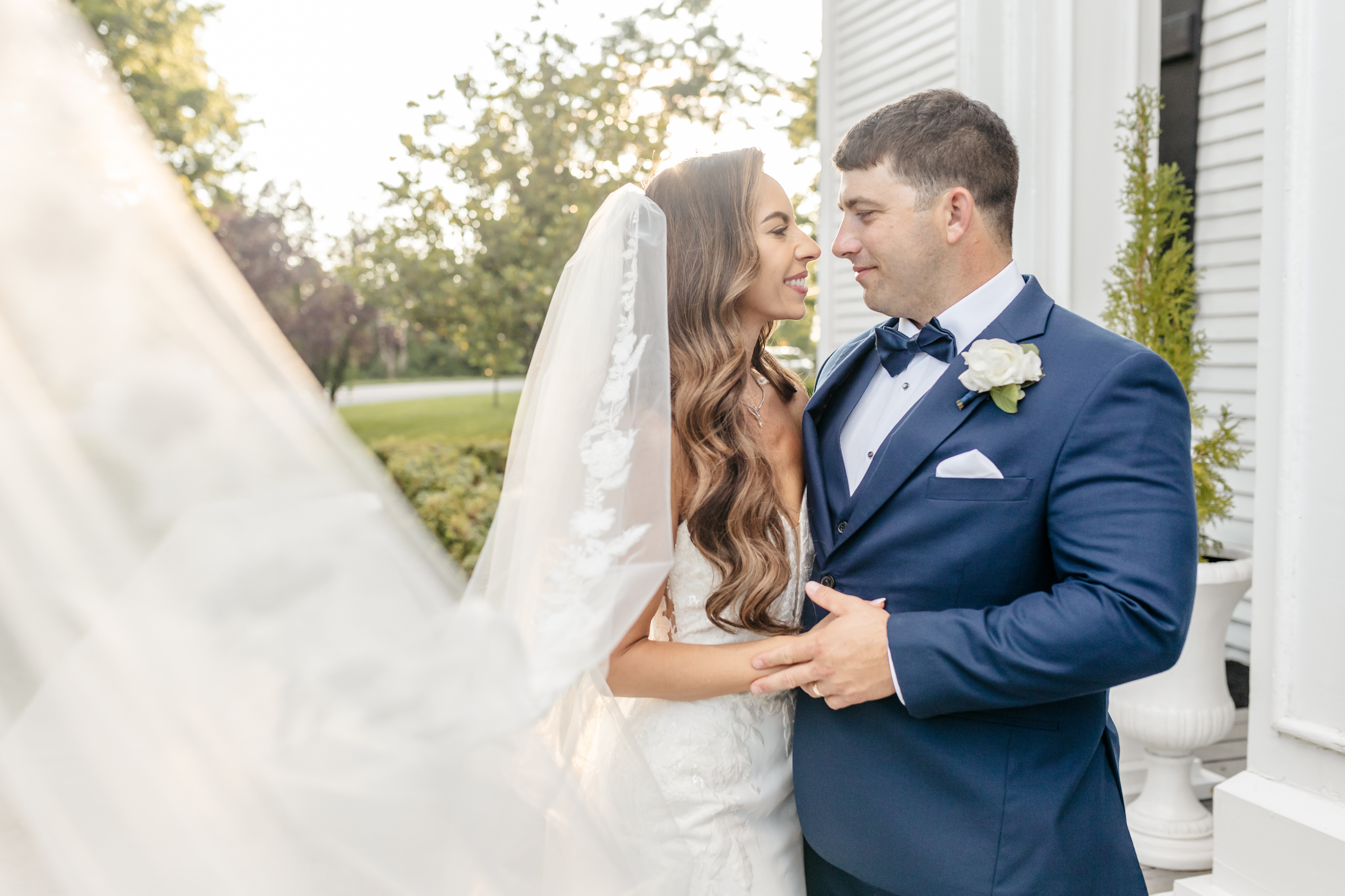 Sweet forehead touch between bride with delicate veil and groom with lavender rose boutonniere