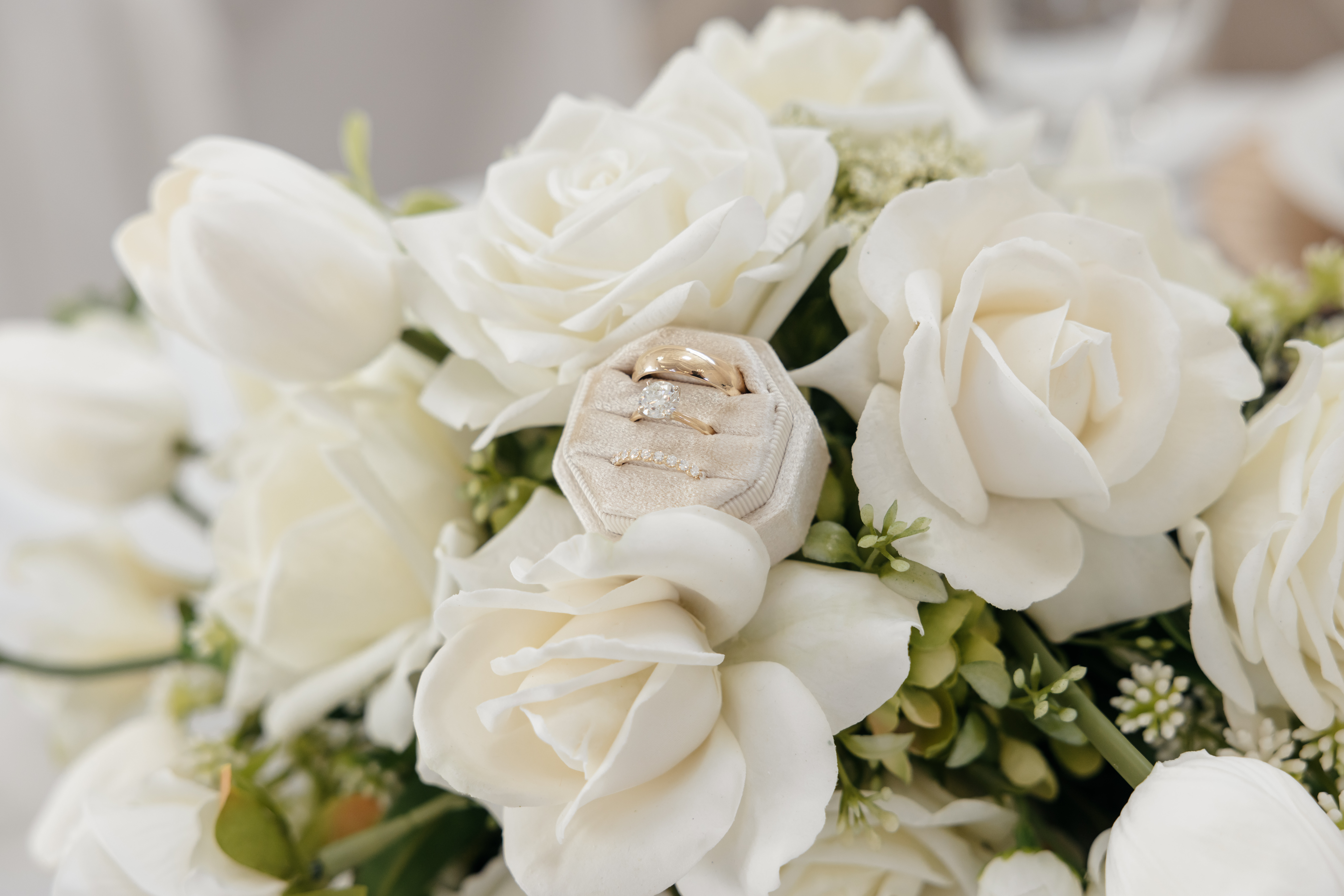 Wedding rings in a velvet box nestled among white rose florals