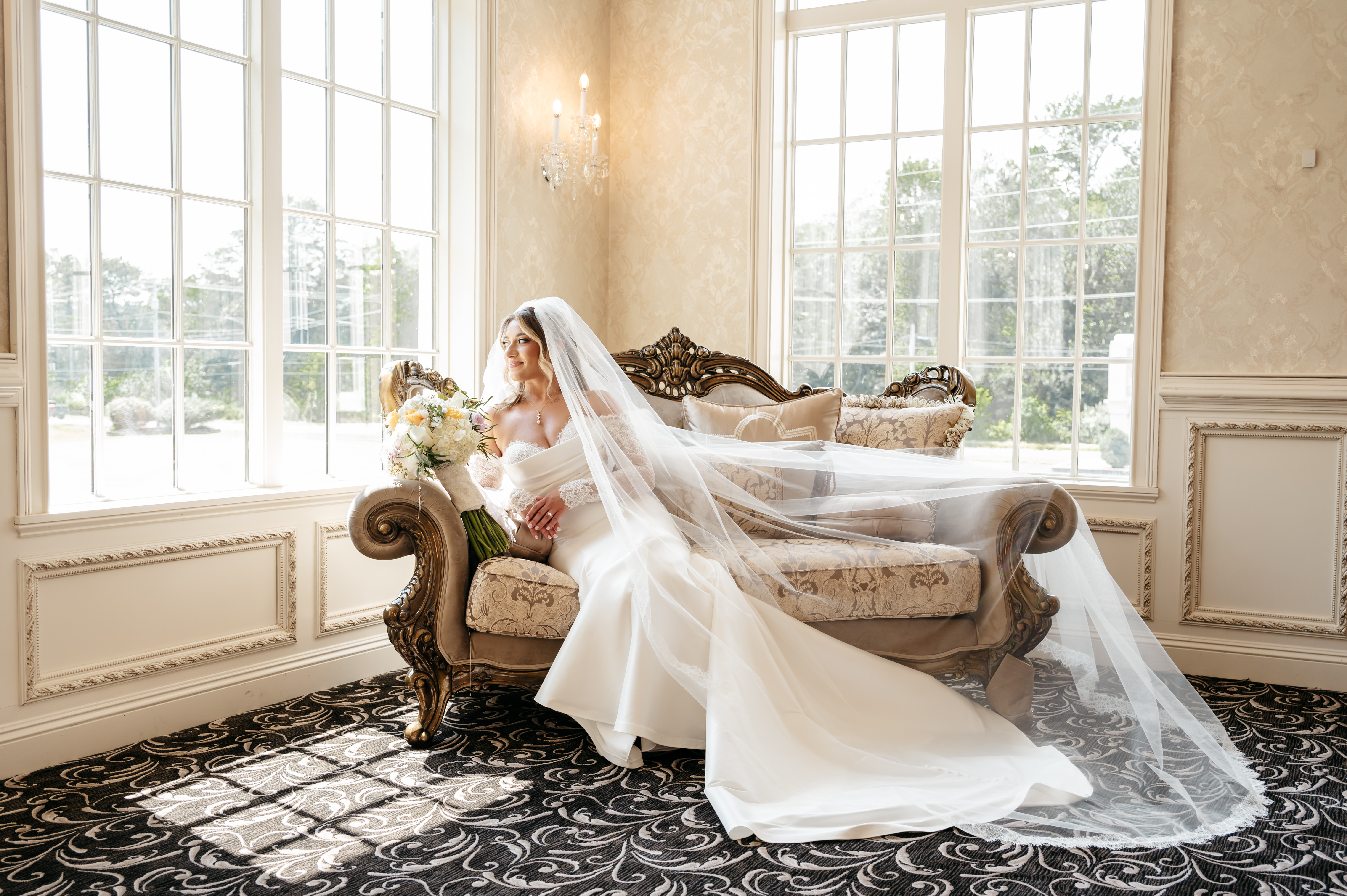 Elegant bride seated on antique settee with flowing veil