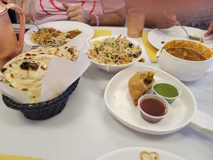 Table feast with golden samosa, sweet and mint chutneys, tandoori naan basket, and curries