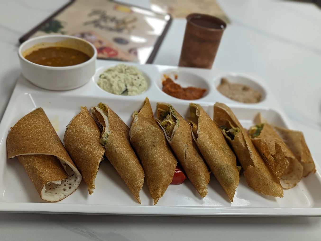 Crisp Dosa platter cut into rolls served with sambar and three signature house chutneys