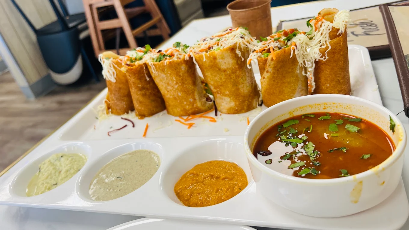 Crisp Spring Dosa rolls topped with cheese, served with hot sambar and three fresh chutneys