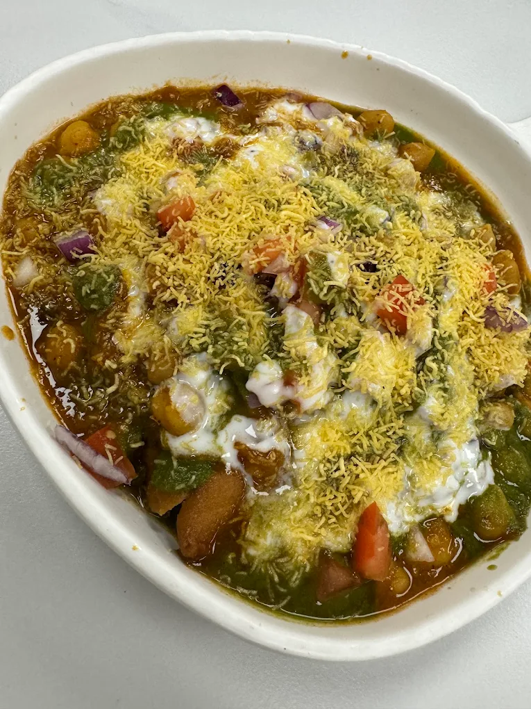 Fresh Samosa Chaat bowl layered with crushed samosas, yogurt, sweet & green chutneys and crispy sev
