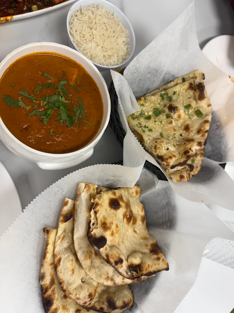 Rich Paneer Butter Masala curry served with fresh warm garlic naan and steamed basmati rice