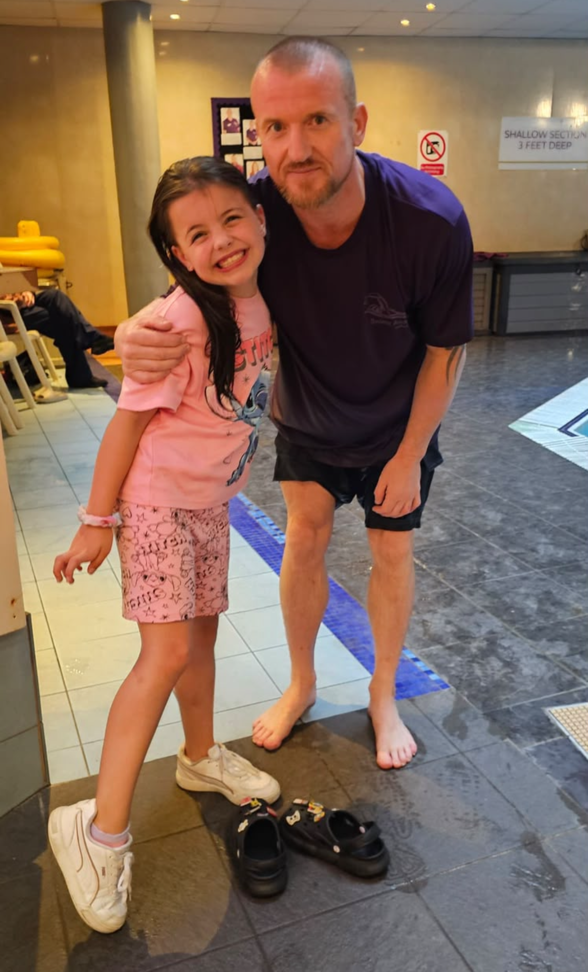 Benjamin Hamlett standing poolside beside a smiling swimming student during a lesson