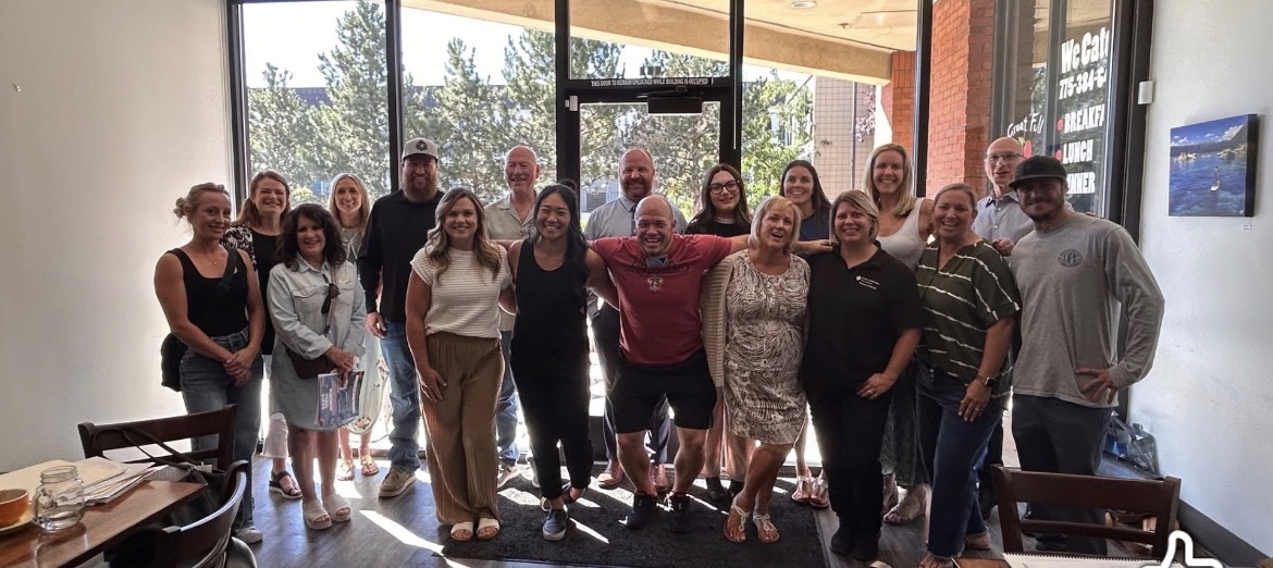 Chapter members gathered together in a group photo by the sunlit venue windows